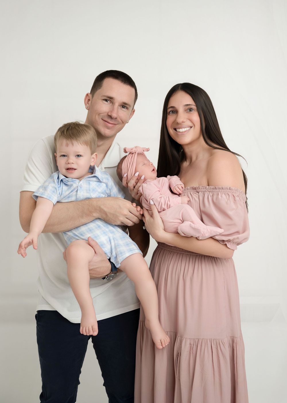 A family in coordinating blue and pink outfits poses together against a white wall in a series of candid shots.