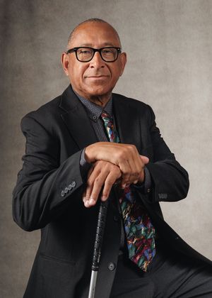 Series of portrait photos showing someone in a dark suit and colorful tie posing expressively with a cane against a gray background.