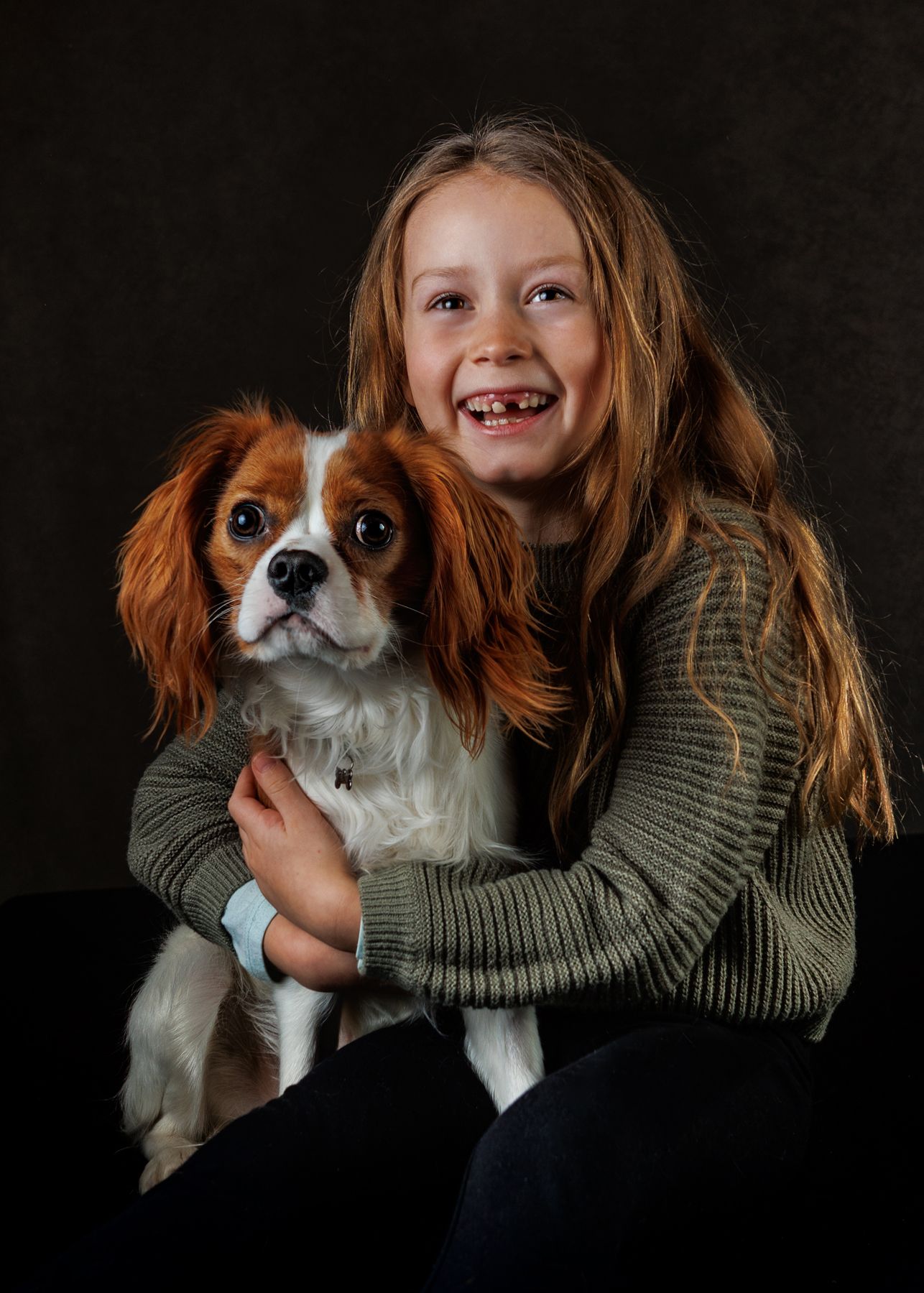 A Cavalier King Charles Spaniel puppy being held in a green sweater shows progression of playful expressions.