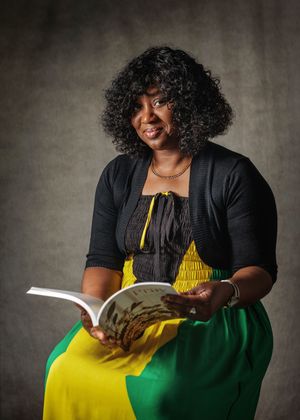 Figure in a black cardigan and bright yellow dress sits reading against a textured gray background.