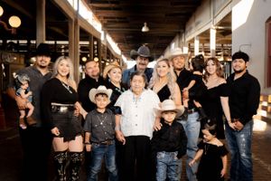 Large family group portrait in western attire posing together in a rustic barn venue setting.