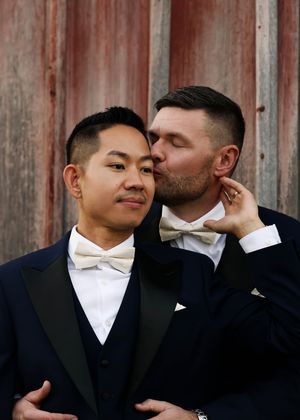 Romantic wedding photos against rustic red barn siding showing intimate moments.