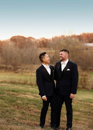 Wedding couple shares joyful moments in formal attire against autumn landscape.
