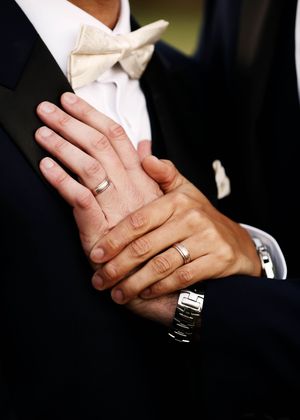 Close-up shots of hands with wedding rings in formal attire.