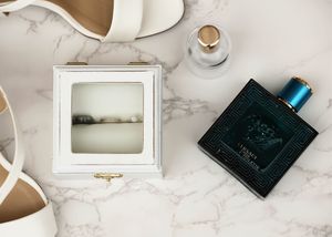 Wedding accessories including perfume bottle and ring box arranged on marble surface.
