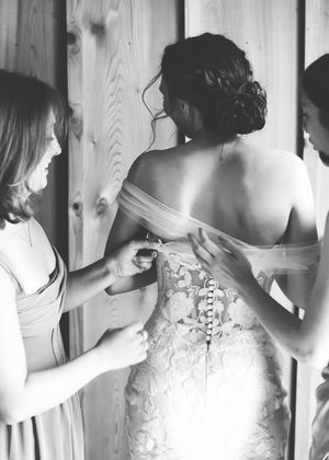 Back details of a white lace wedding dress are shown in multiple angles against wooden paneling.