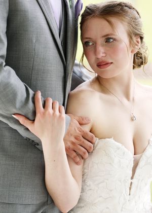Close-up details of a wedding couple embracing, showing dress and suit details.