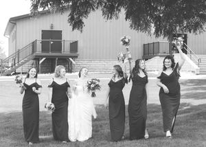 Wedding party poses playfully in black and white photo outside a church building.