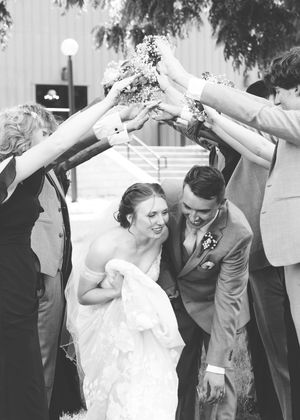 Wedding couple ducking under raised arms during a celebratory moment.