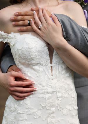 Close-up details of a white lace wedding dress bodice with delicate floral appliques and intricate beading.