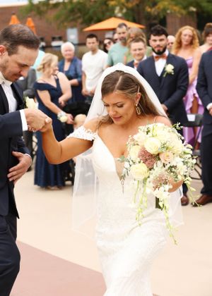 Couple celebrates with joyful dance moves during outdoor wedding ceremony.