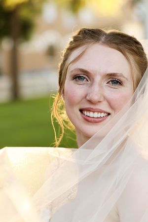 Ethereal bridal portrait with flowing veil in warm golden sunlight.