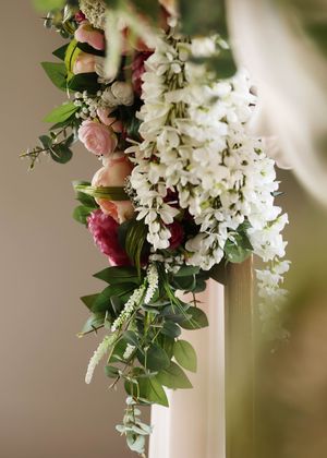 Elegant white floral arrangements with greenery and pink accents decorating a wedding venue.