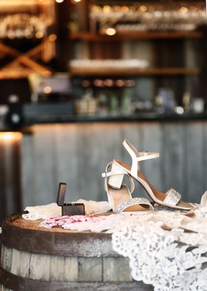 Wedding shoes displayed on delicate white lace against a wooden surface.