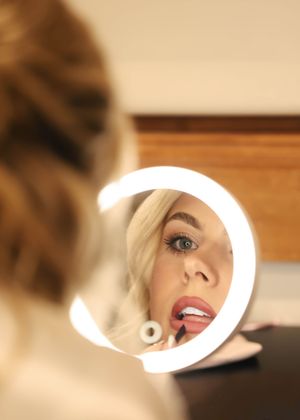 Artistic bridal beauty shots captured through a circular mirror with dramatic lighting.