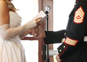 A bride and Marine Corps servicemember exchange rings during their wedding ceremony.