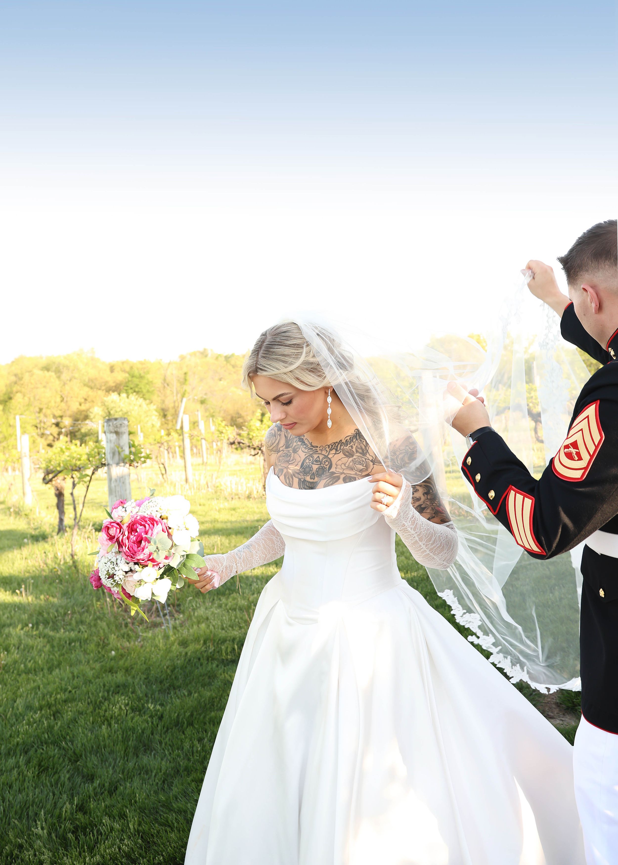 Wedding couple celebrates outdoors with flowing white dress in sunlit field.