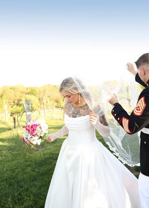 Wedding couple celebrates outdoors with flowing white dress in sunlit field.