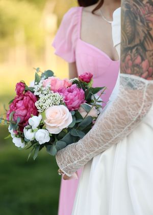 Pink and white wedding bouquets with roses and greenery against lace dress details.