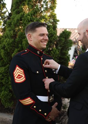Marine Corps servicemembers adjust formal uniforms before ceremony.