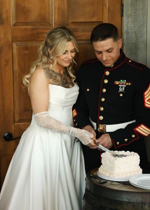 A military wedding couple shares a moment cutting their wedding cake together.