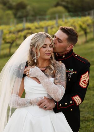 A romantic wedding photoshoot in a vineyard with a white dress and military uniform at sunset.