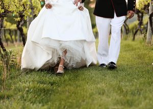 Wedding couple's feet and dress details captured in a vineyard setting.