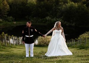 Wedding couple walking through a lush green vineyard landscape.