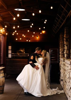 Romantic dance poses in a rustic venue with stone walls and string lights.
