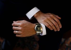Close-up of hands wearing formal suits and watches.