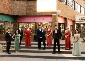 Wedding party poses outside a vintage building with red and green accents.