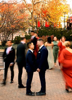 Motion blur photo of wedding party on brick pathway with fall foliage.