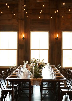 Rustic wedding reception venue with long tables and string lights.