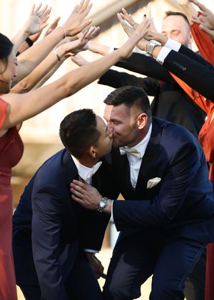 Wedding party forms tunnel for couple during celebration moment.