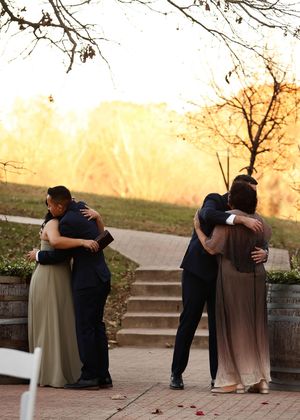 Two couples embrace during an emotional sunset moment on stone steps.