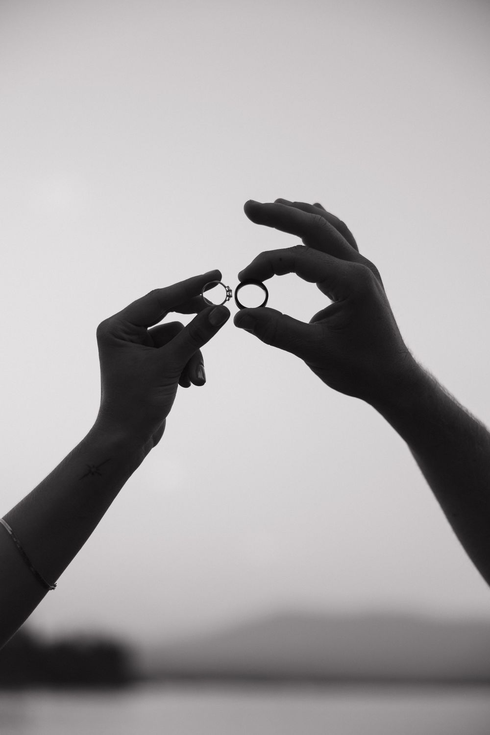 A sequence of silhouetted hands against a blurry background shows the stages of putting on an engagement ring.