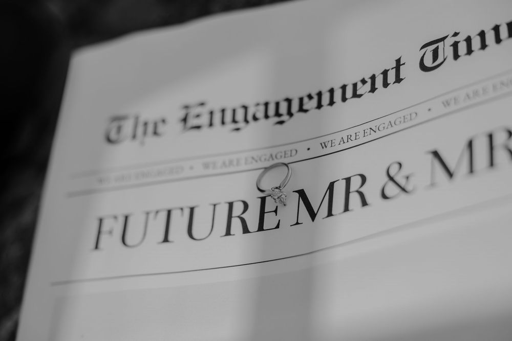 Blurred text from newspaper headlines and columns creates an abstract black and white background pattern.