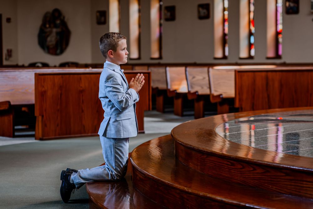 A boy kneels in reverence for an emotional first holy communion picture