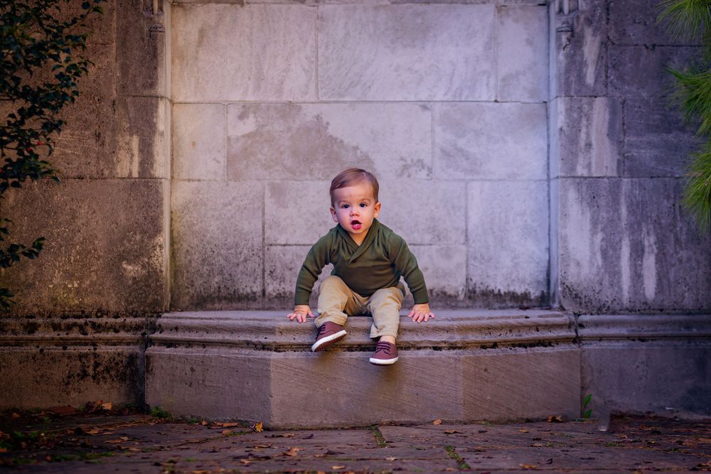 Little boy running toward the camera during a playful outdoor photoshoot.