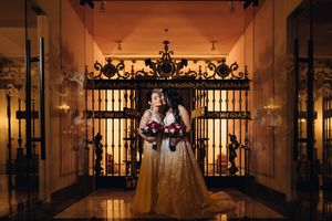Elegant wedding venue with ornate iron gates and romantic lighting creating a dramatic silhouette of the couple.