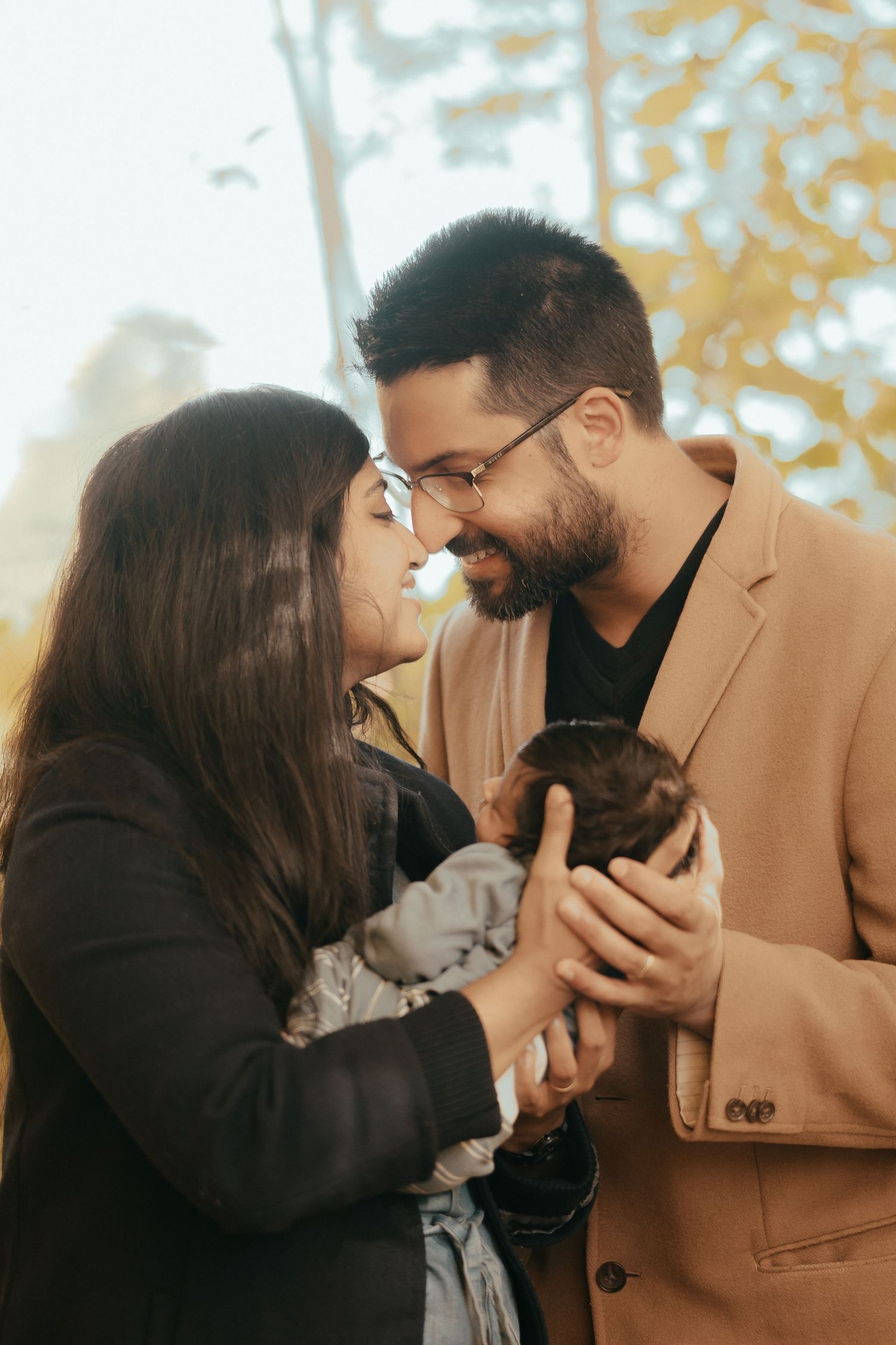A tender family moment showing parents cradling their newborn baby in a cozy indoor setting.