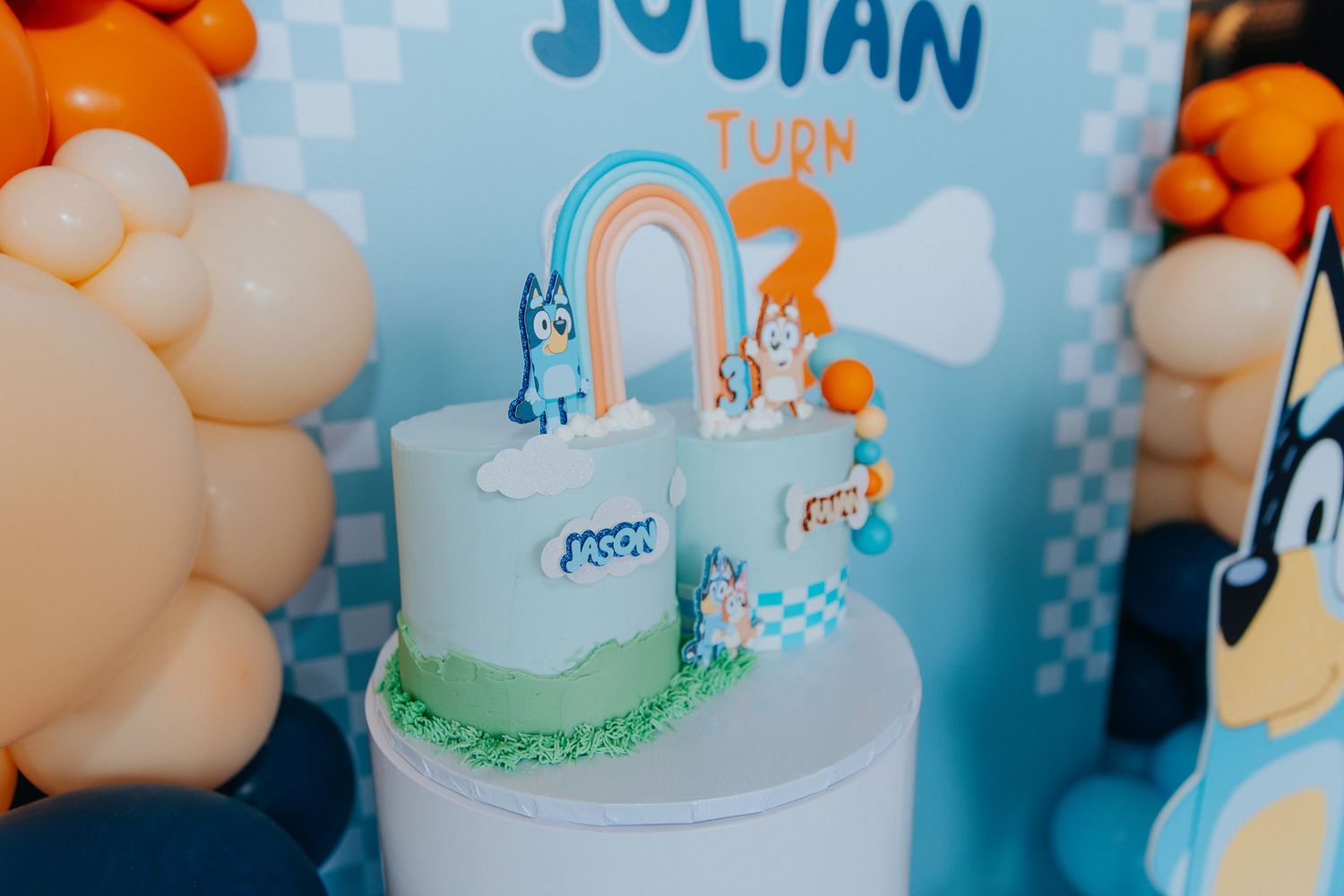 Bluey themed birthday cake for Julian turning 3, decorated with cartoon figures and a rainbow topper.