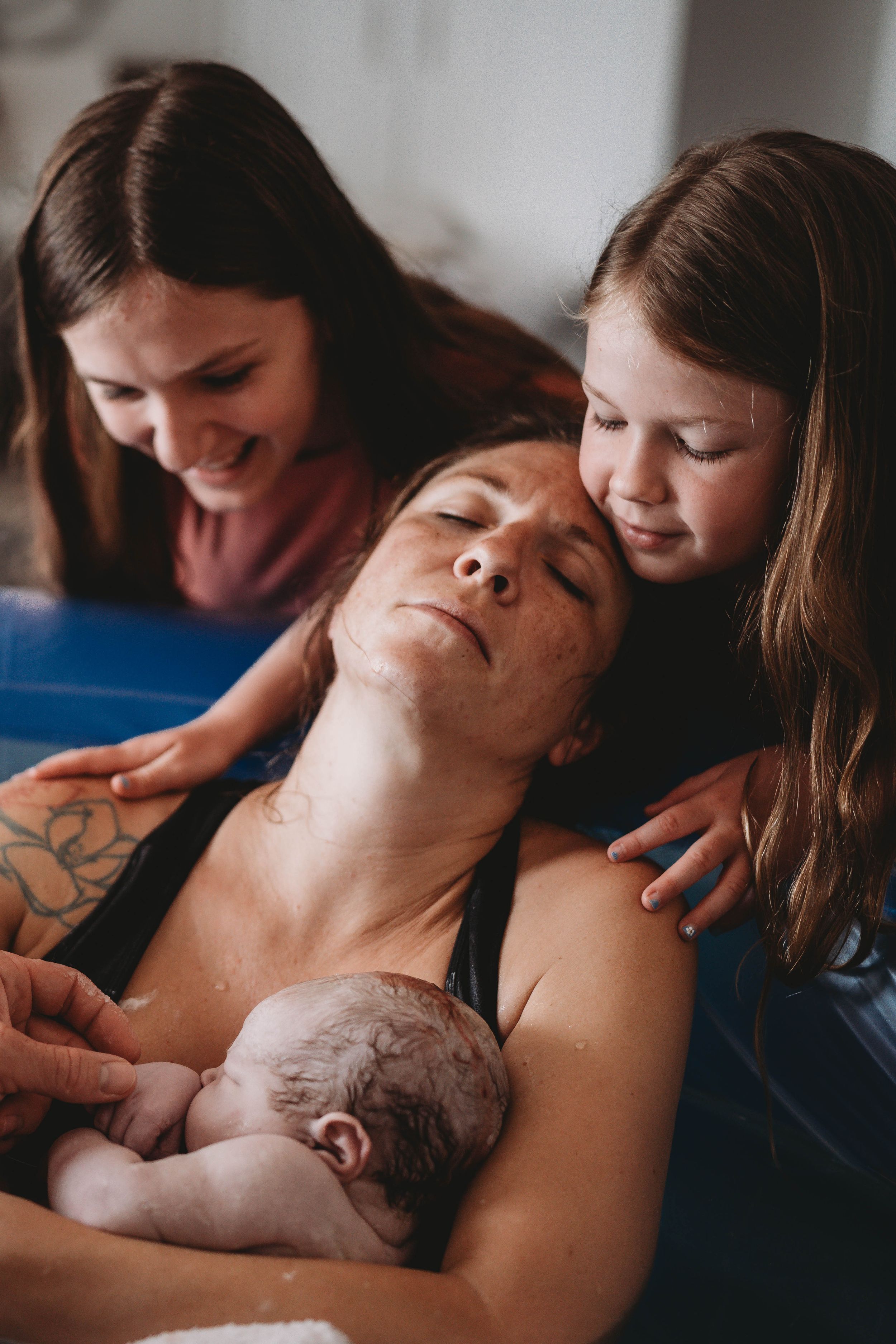 Intimate Palm Beach home birth scene showing skin-to-skin contact with newborn baby surrounded by supportive care team.