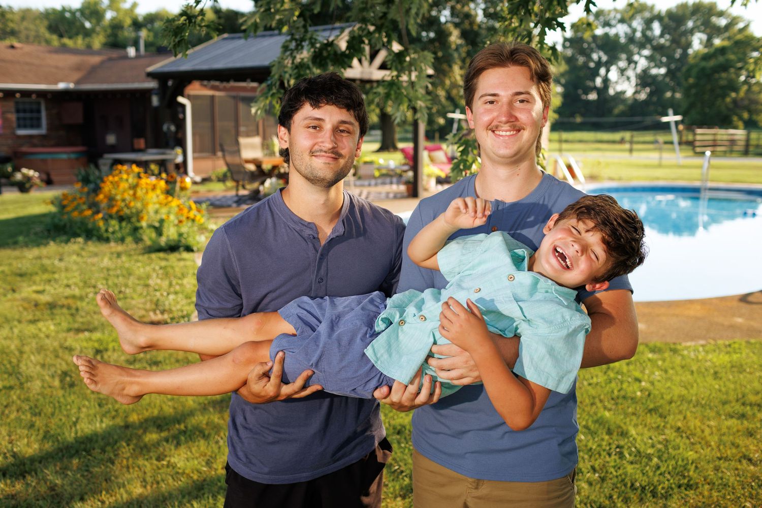 Big brothers holding little brother across their arms horizontally during a break in their Mattoon, Illinois family photography session.