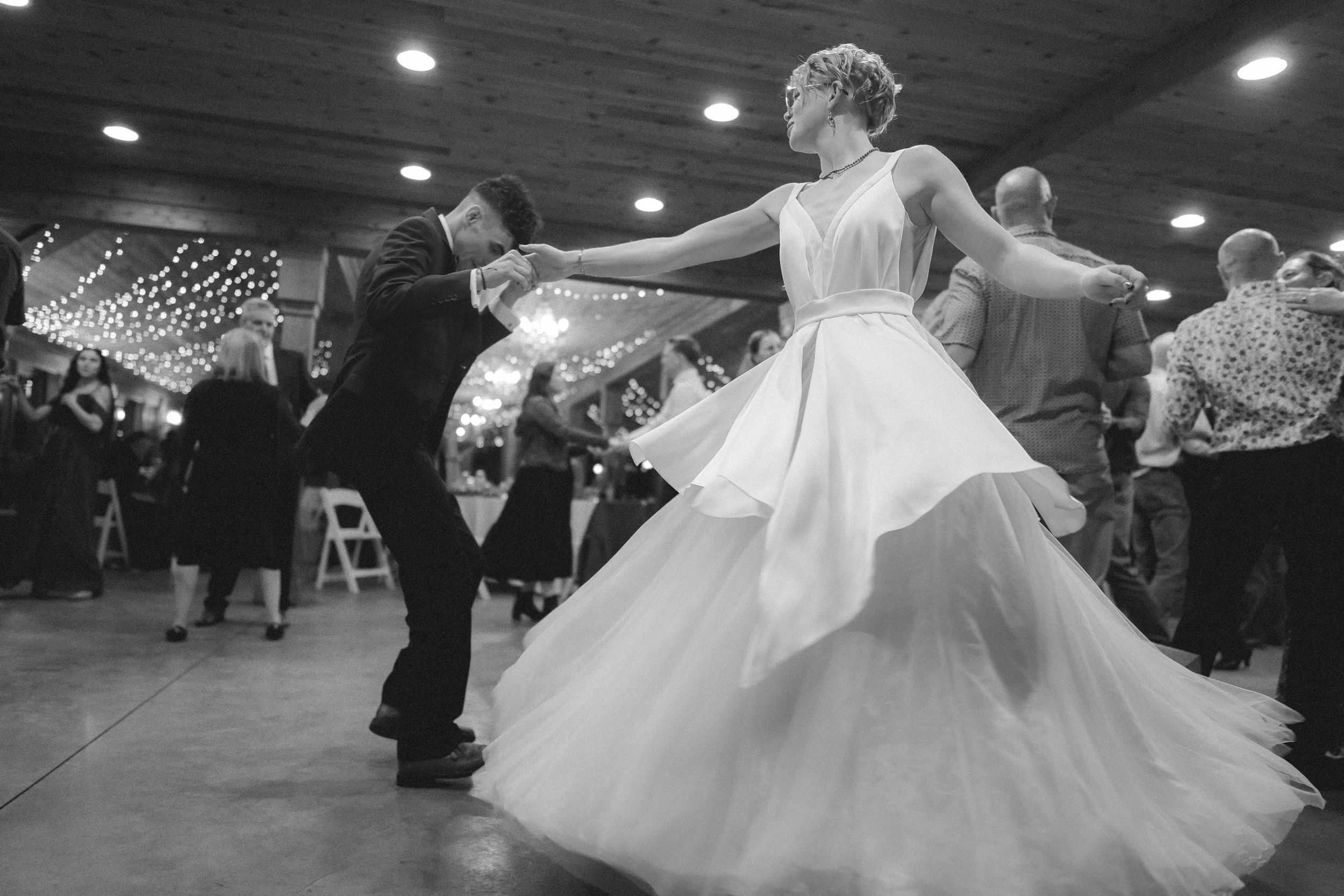 Couples dance together at a formal event as a bride's white dress twirls gracefully on the dance floor.