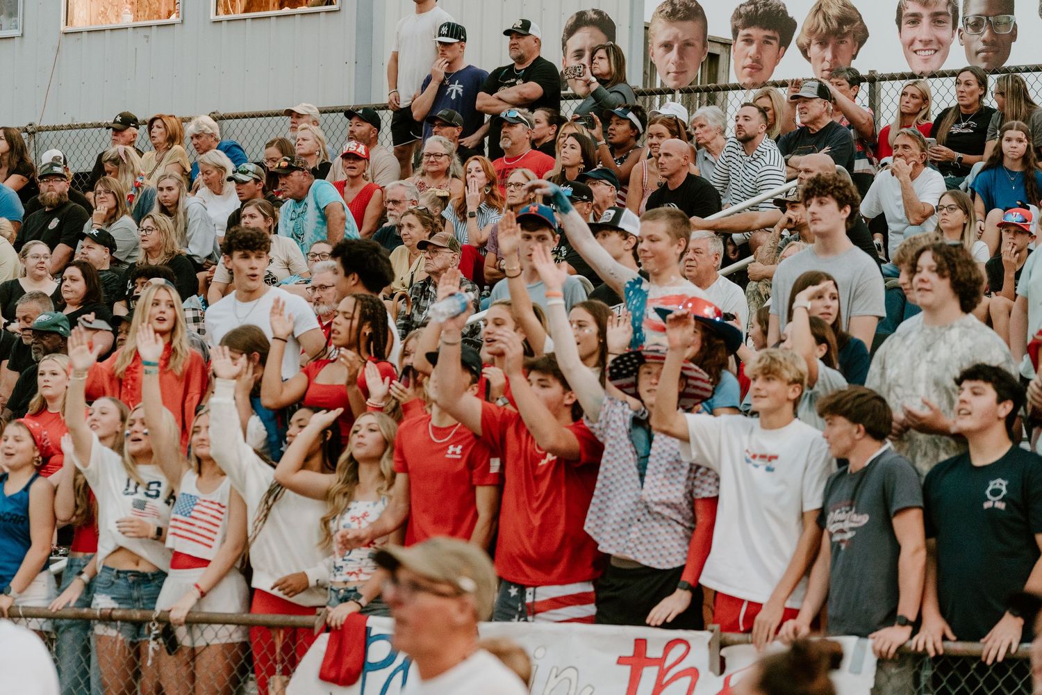 Large crowd of enthusiastic students cheering in bleachers at a sporting event.