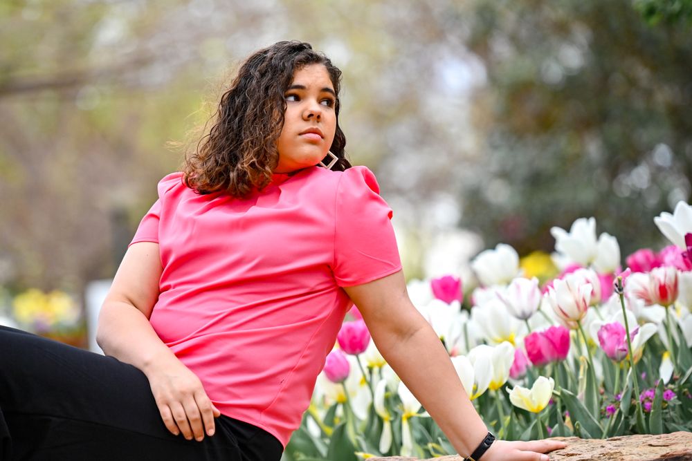 A person in a pink shirt relaxes among blooming tulips on a spring day.