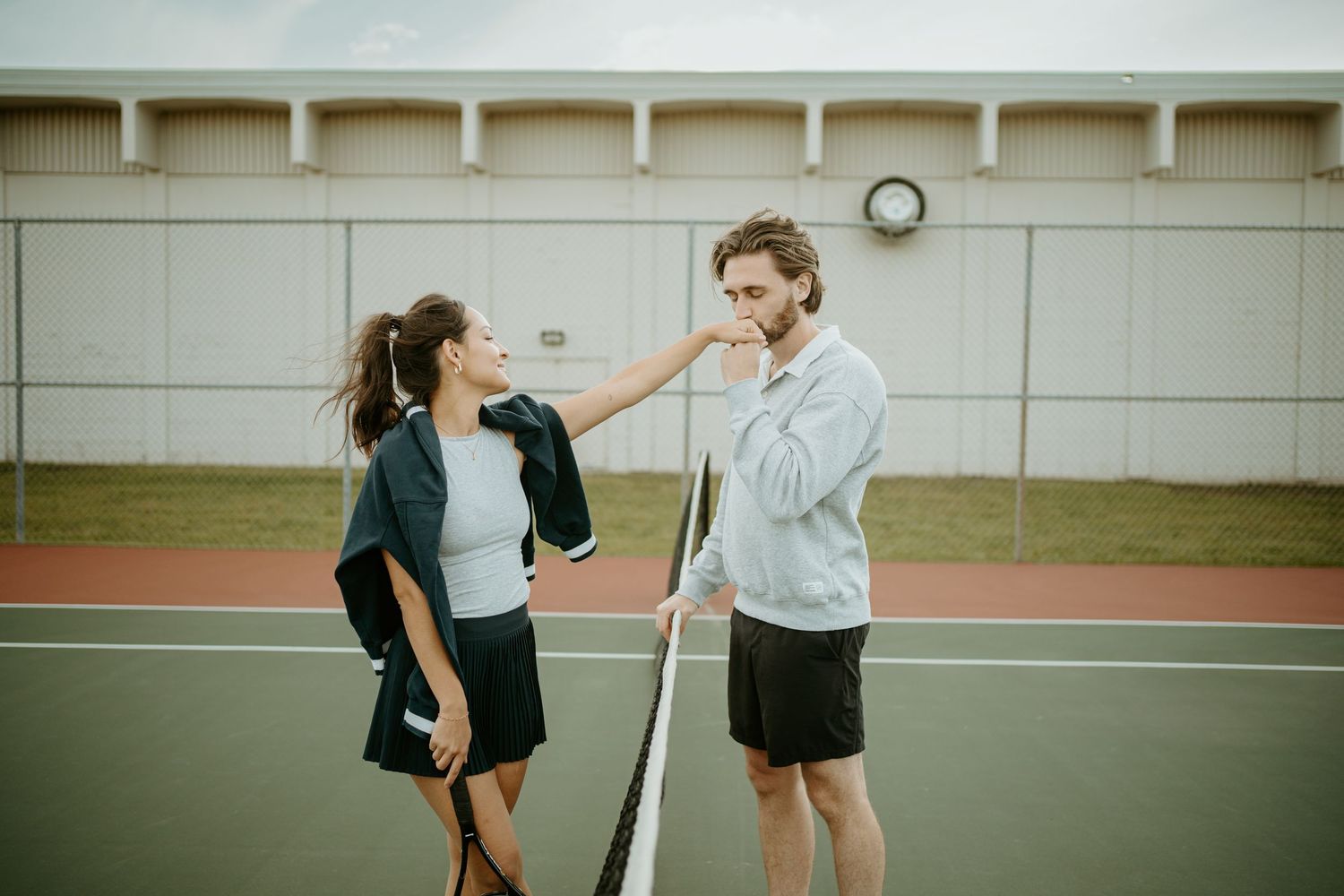 Two people play a doubles pickleball match on an outdoor court during an overcast day.