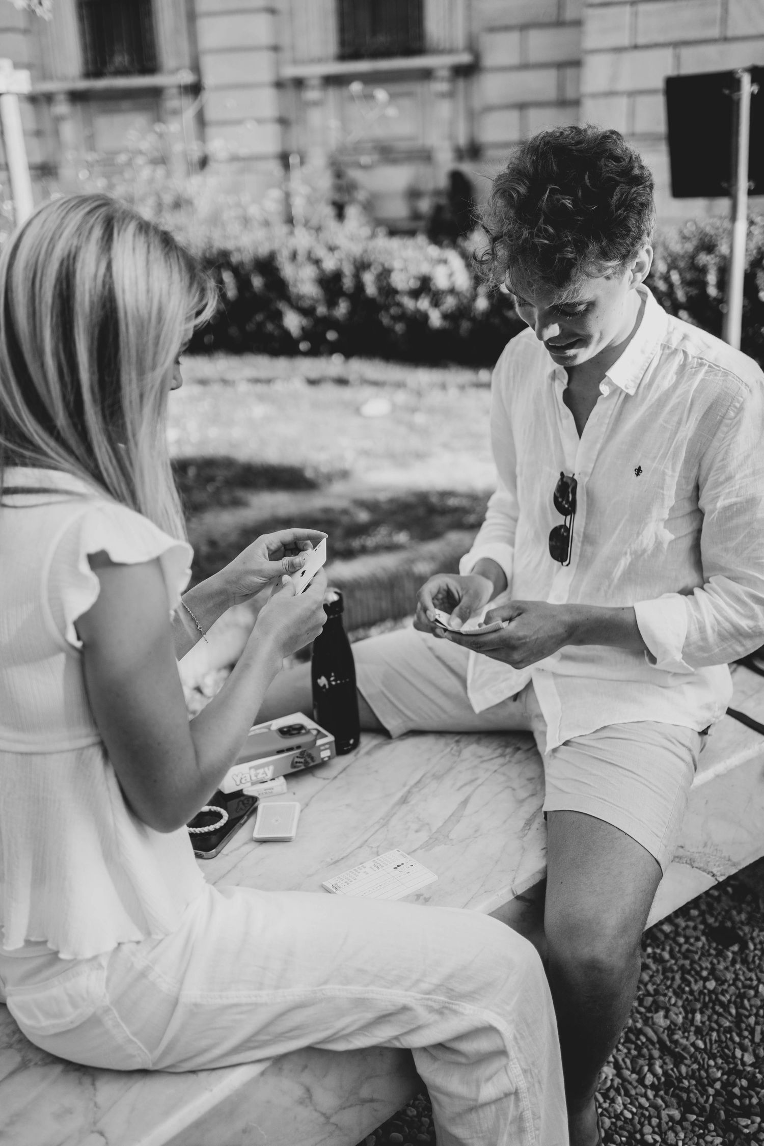 A casual outdoor card game between two people in summer attire.