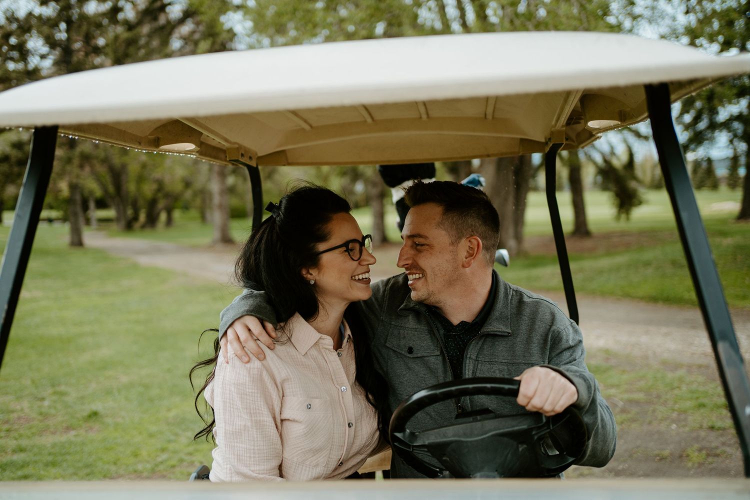 A couple shares a tender moment while sitting in a golf cart on a sunny day.